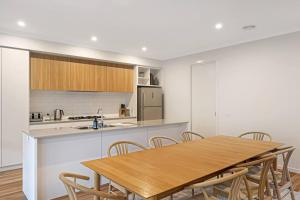 オーシャン・グローブにあるMadeley Family Getaway- Sleeping 8, central, aircon, close to shops, beach, parks, spaciousの木製のテーブルと椅子のあるキッチンとダイニングルーム