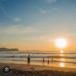 a group of people standing on the beach at sunset at depa playa in Arica