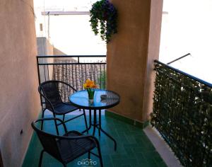 ein Tisch mit Stühlen und einer Vase mit Blumen auf einem Balkon in der Unterkunft Corte Antica Luxury in Ravanusa