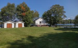a house on a grassy field with a lake at Cozy Lakeside Cottage with Beautiful Sunsets in McDougall +13 photos