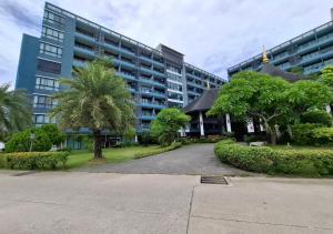a large building with palm trees in front of it at Baan Bangsarey Hotels in Bang Sare