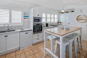 una cucina con mobili bianchi e un tavolo di legno di Seagate Escape at Caloundra a Caloundra
