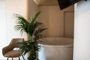 a bathroom with a tub and two plants and a chair at B&B Stellamarina in Pulsano