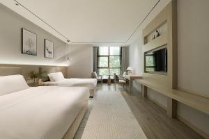 a hotel room with two beds and a television at 凯瑞汀酒店 重庆西站巴国城店 in Chongqing