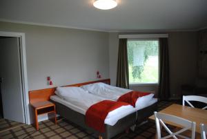 a bedroom with a bed and a table and a window at Fleischer's Motel in Vossevangen +21 photos
