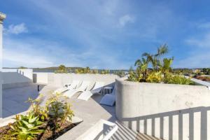 a patio with white chairs and a view of the ocean at Elegantly Spacious 3-Bed Unit Overlooking the Bay in Batemans Bay