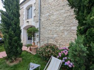 a stone house with a bench in the yard at Appartement historique avec piscine, salle de jeux, et jardin - idéal famille et amis - FR-1-653-261 in Angoulême