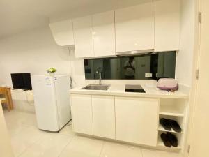 Una cocina blanca con fregadero y refrigerador. en Pattaya City Center Residence by K2, en Pattaya central