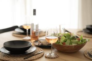 a table with a bowl of salad and a glass of wine at Blueholes Beach Villa - Private Outdoor Space in Kalbarri