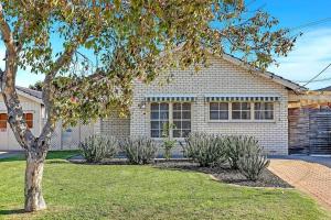 a house with a tree in the front yard at West Beach Hideaway - A Relaxed Coastal Locale in Adelaide