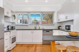 a kitchen with white cabinets and a counter top at West Beach Hideaway - A Relaxed Coastal Locale in Adelaide
