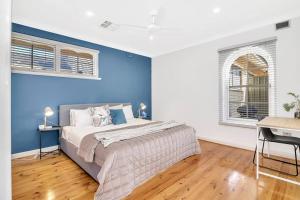 a bedroom with a blue wall and a bed at West Beach Hideaway - A Relaxed Coastal Locale in Adelaide