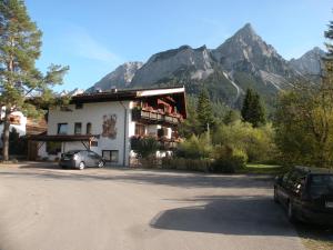 a building with cars parked in front of a mountain at Tyrol Appartements in Ehrwald