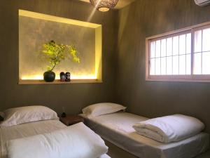 two twin beds in a room with a window at 静雅の宿 in Kyoto
