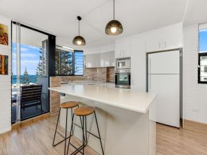 カラウンドラにあるRyson Unit 7 Kings Beach QLDのキッチン(大きな白いカウンター、スツール付)