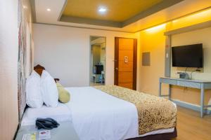 a hotel room with a bed and a flat screen tv at La Piazza Hotel and Convention Center Inc. in Legazpi