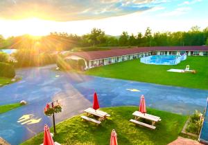 a swimming pool with tables and umbrellas in front of a building at Hotel Motel Bonsoir in Granby