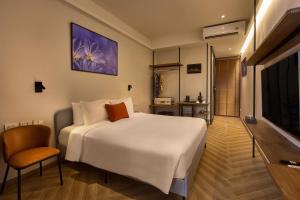 a bedroom with a large white bed and a television at Red Door Samsen Hotel, Bangkok in Bangkok