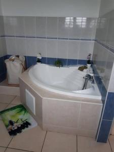 La salle de bains est pourvue d'une baignoire blanche et de carrelage bleu. dans l'établissement Entre mer et montagne, à Le Tampon 4 autres photos