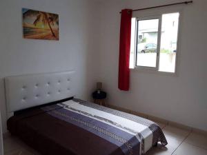 - une chambre avec un lit doté d'un rideau rouge et d'une fenêtre dans l'établissement Entre mer et montagne, à Le Tampon