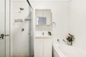 シドニーにある8 mins from Sydney Airport! 1BR with Courtyardの洗面台とシャワー付きの白いバスルーム