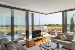 a living room with large glass windows and a tv at Villa Pliades in Ayia Napa