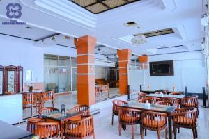 a restaurant with tables and chairs and a tv at Bandung Permai Hotel Jember in Jember