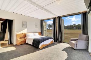 a bedroom with a bed and a chair and windows at Containers on Kidston in Mansfield
