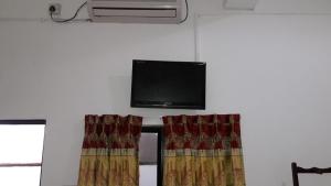 a room with a flat screen tv and curtains at Blue Ocean Hotel in Trincomalee