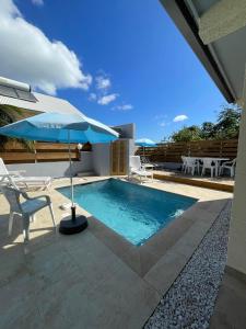 - une piscine avec un parasol bleu, une chaise et une table dans l'établissement La villa Cannelle maison 1, à L'Étang-Salé