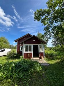a small red and white house in a field at Peltosaaren Luomulammastila in Salo