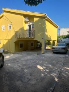 a yellow building with a car parked in front of it at SNG Apartmani in Brca