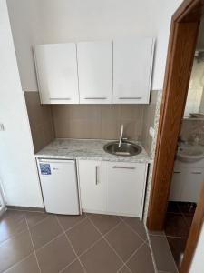 a kitchen with white cabinets and a sink at SNG Apartmani in Brca +2 photos