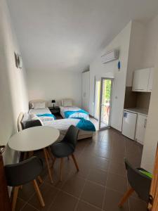 a room with two beds and a table and chairs at SNG Apartmani in Brca