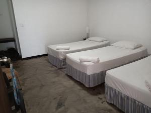 - 3 lits dans une chambre aux murs blancs dans l'établissement Aligama Cottage, à Talakolawela