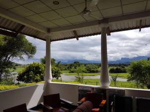 d'un balcon avec des chaises et une vue sur un champ. dans l'établissement Aligama Cottage, à Talakolawela