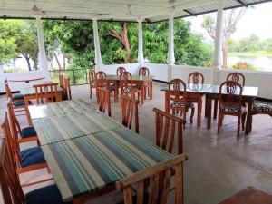 un restaurant avec des tables et des chaises en bois avec vue sur l'eau dans l'établissement Aligama Cottage, à Talakolawela