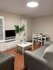 a living room with a couch and a tv and a table at Apartamento vacacional playa in Almería