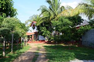 a dirt road in front of a house with trees at Aastha homestay in Mysore