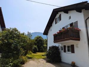 a white building with a balcony with flowers on it at Landhaus Heck in Pfronten