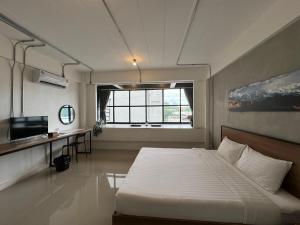 a bedroom with a bed and a desk and a window at Luka House in Lam Luk Ka