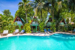 une piscine dans un complexe hôtelier avec des chaises et des palmiers dans l'établissement Phuket Meet Holiday Hotel-Rawai 普吉岛相遇花园度假酒店-拉威店, à Rawai Beach