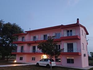 a pink building with a car parked in front of it at Pefki Apartment 4 in Artemísion +5 photos