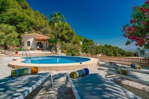 a swimming pool with two benches and a house at Casa Coromandel in Calpe