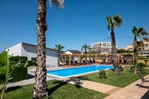 a resort with a swimming pool and palm trees at Paradise Apartments Artemida in Artemida