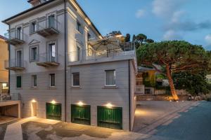 a white building with green windows and a tree at VILLA CADIZ APARTMENTS VARAZZE in Varazze