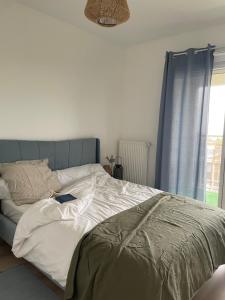 a bedroom with a bed with a blue headboard and a window at Bienvenue chez nous in Noisy-le-Grand