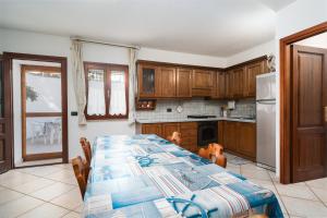 Una cocina con una mesa con sillas y un refrigerador. en Confortevole e fresco seminterrato, en Siniscola
