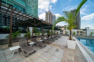 a row of chairs and umbrellas next to a pool at St Giles Boulevard in Kuala Lumpur