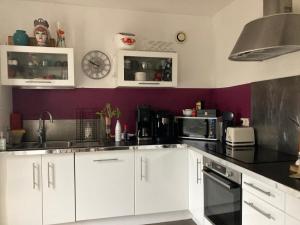 a kitchen with white cabinets and a purple wall at Villa Rose Suite et chambres chez l'habitant in Montpellier
